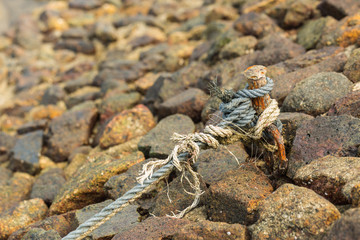 old rope tied with rusty iron on rock