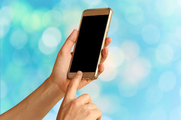 Smartphone on hand over blurred light bokeh background,abstract background for technology concept.