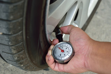 Hand holding pressure gauge for car tyre pressure measurement