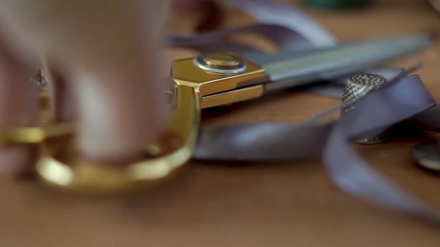 Taylor picks up the scissors from the table