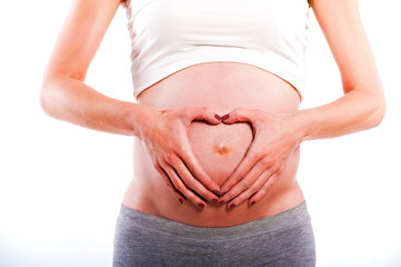 Pregnant Woman holding her hands in a heart shape on her baby bu