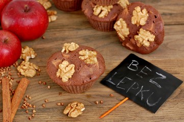 Obraz na płótnie Canvas Gluten free muffins from buckwheat flour, apple, cinnamonand walnuts on brown wooden background with index card with text no gluten in czech language