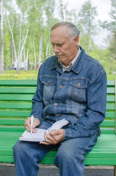 Aged man is making notes in the daily planner