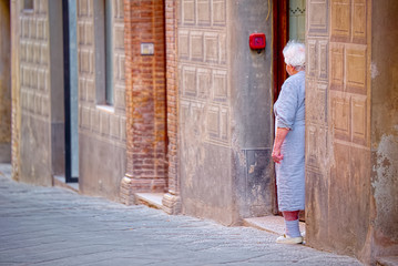 Elderly woman waits outside the house in Montalcino, Tuscany
