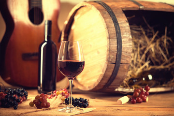 Wine bottle, glass, grapes, barrel and guitar 