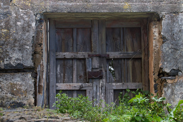 Old wooden door or gate and metal wires of the rusted lock. Outside the house, village, everything comes into disrepair