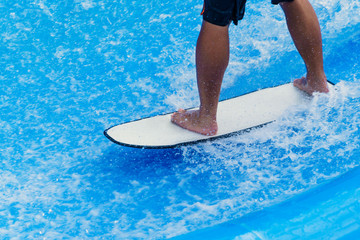 Man's legs standing on surfboard