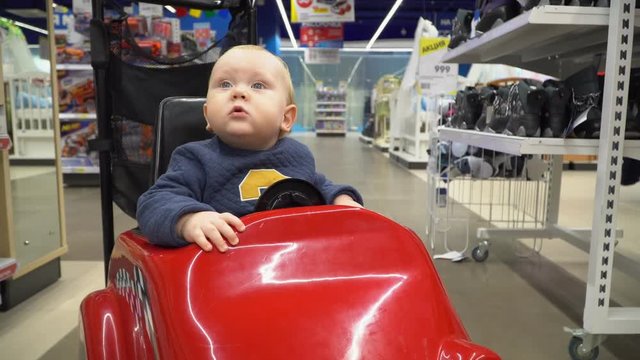 Baby sitting in the shopping cart in a store.