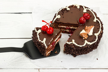 Chocolate cake with cherry on wooden background