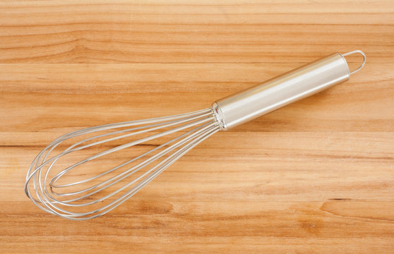 Kitchen mixing whisk on wooden surface.