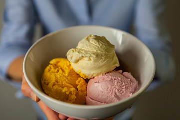 Hands Holding Bowl of Vanilla, Mango and Strawberry Ice Cream