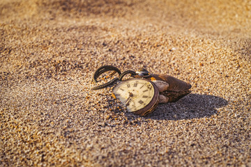 Fototapeta na wymiar Still life - Antique rotten pocket watch buried partial in the sand