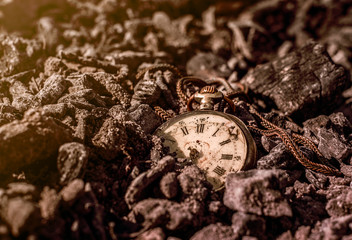 Still life - antique rotten pocket watch on ashes in the forest at the sunset.