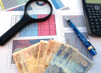 business and financial success concept: magnifier, calculator, bank notes, pen and documents