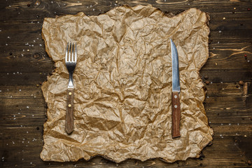 Blank parchment paper sign by cast iron spoon and fork rustic wood background