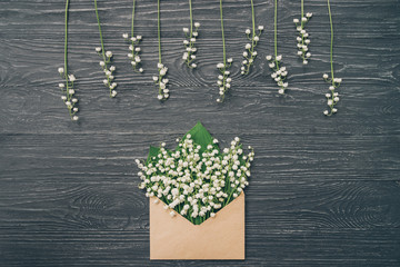 Lily of the valley on gray wooden background. Top view of lily of the valley bouquet in craft...