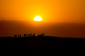 Sonnenuntergang in der tunesischen Wüste mit Menschensilhuetten am Horizont