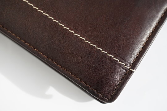 Macro detail of a white and brown thread stitching black and brown stitched leather wallet