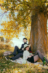 Fototapeta premium Pareja joven pasando un día de otoño en el campo haciendo un picnic 
