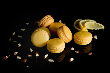 Whole and broken orange lemon homemade macaroons , lemon slice and zest and citrus sugar on stone slate board over black background.