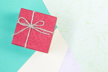 Red gift bow top view on color paper background with copy space.
