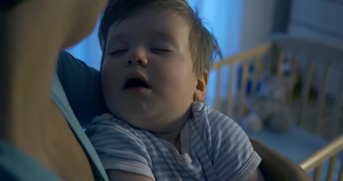 Adorable Baby Sleeping In Mother's Arms - Night Shot.
