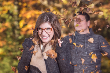 Mann wirft Herbstlaub von hinten über seine Partnerin
