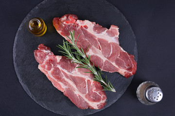 Raw pork loin chops black background, spices, olive oil. Cooking background, healthy eating concept.