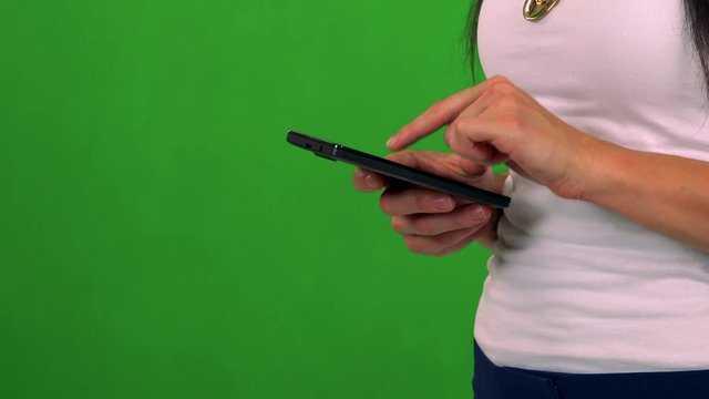 young woman works on smartphone (typing)- green screen - studio 