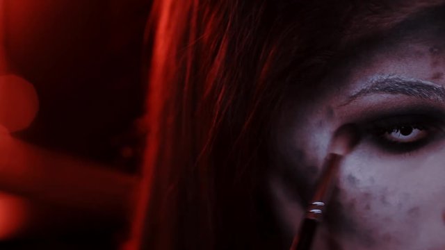 girl makes a make-up in the style of a witch Halloween