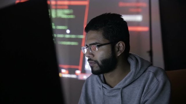 Arabic IT specialist working on computer at night. Hacker breaking computer code. HD.
