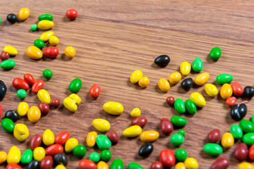 Colorful candy scattered on the wooden table.