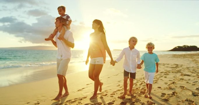 Happy family walking down the beach at sunset