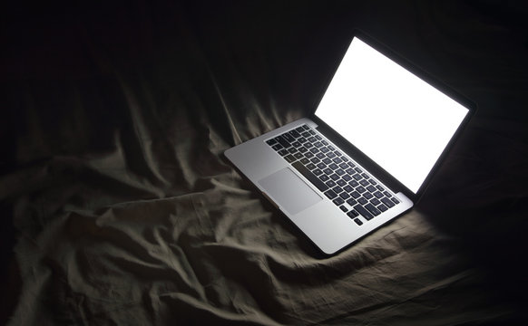 Laptop in bed. Night working at home concept image with copyspac
