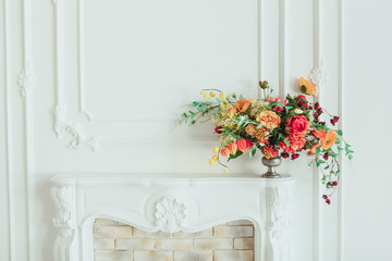 autumn bouquet on the fireplace. The cozy interior in white tones