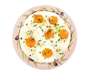Fried eggs on ceramic plate with salt, pepper and green onion isolated on white background