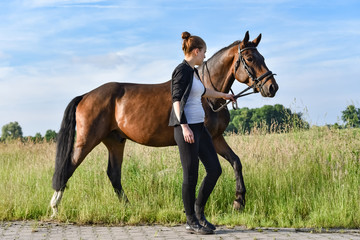 Attraktives Mädchen führt ihr Pferd am Zügel