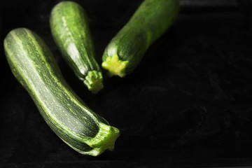 Fresh green zucchini on black baking tray