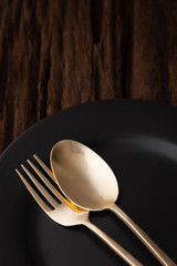 black empty plate fork spoon on wooden table background