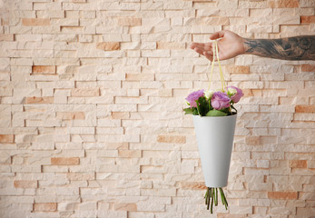 Male hand holding beautiful bouquet on blurred brick wall background