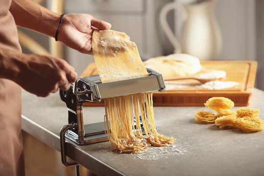 Man using pasta machine to prepare spaghetti, close up view