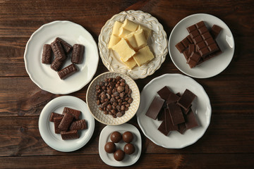 Many plates with chocolate on wooden background, top view