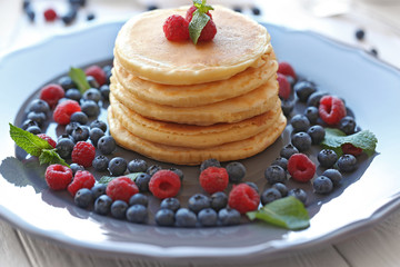 Plate with tasty pancakes and berries on wooden table, close up view