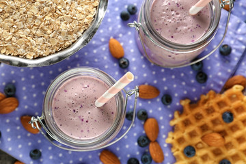 Two mason jars with tasty smoothie, straws and some ingredients on grey table, close up view