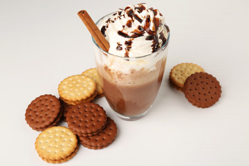 Glass of delicious milk shake with whipped cream and chocolate topping on light background