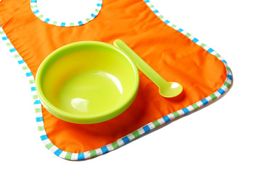 Bright baby tableware and bib on white background