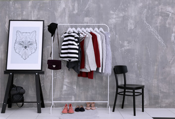 Fashionable clothes hanging on rack at modern dressing room