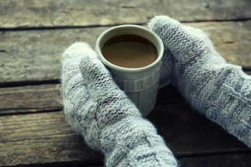 Female hands holding hot drink on windowsill