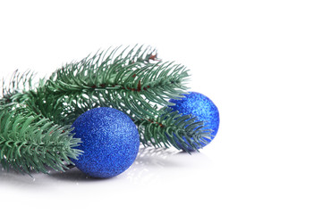 Composition of blue baubles and coniferous branch on white background