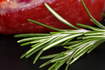 Rosemary and raw meat steak on black background. Fresh, raw, organic vegetables. Cooking, Healthy eating concept.